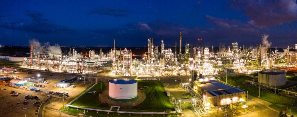 pexels-photo-10396413 Aerial night view of a brightly lit industrial oil refinery with smoking chimneys in Rosemount, MN, USA.